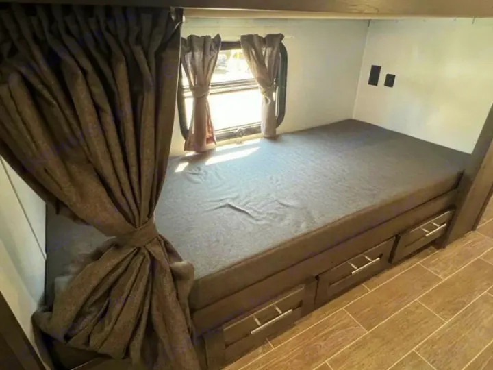 Cozy RV rental bunk bed with convenient storage drawers and a window view, ideal for family travel.. Forest River Georgetown GT5 2023