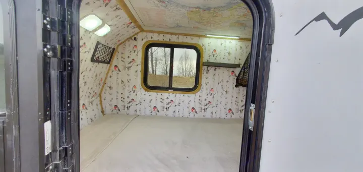 Explore this cozy RV rental interior: comfortable bed, unique bird & birch wall decor, map ceiling, and bright lighting.. Haulmark Homesteader 2005