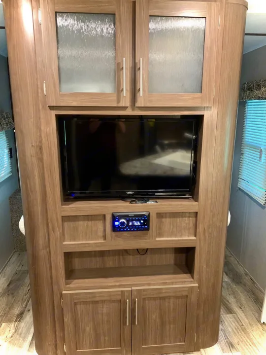 RV rental interior: A functional wood entertainment center with TV, stereo, & storage options.. Keystone RV Hideout LHS 2019