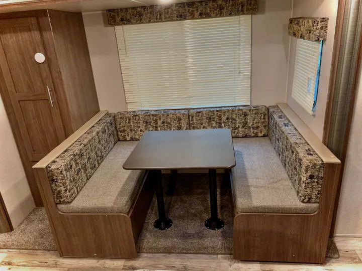 RV rental dinette: U-shaped wood-look booth seating, table, and blinds. Perfect for RV travel.. Keystone RV Hideout LHS 2019