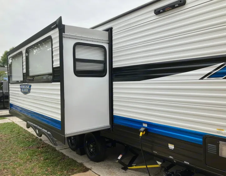 White travel trailer RV rental, slide-out extended. Parked with blue/black accents; ideal for trips.. Forest River Salem Cruise Lite 2023