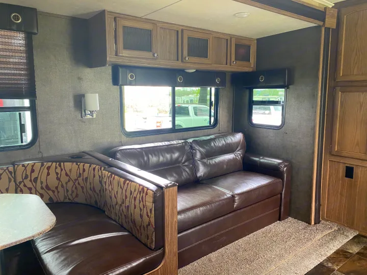 Spacious RV rental interior with brown leather sofa, dinette, overhead cabinets, and windows for comfortable living.. Forest River Shasta Revere 2016