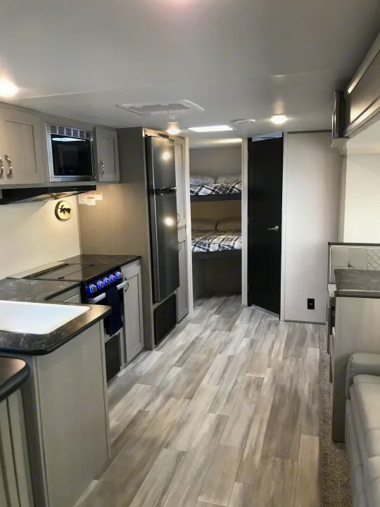 Spacious RV rental interior featuring a modern kitchen with stove, microwave, fridge, and bunk beds. Perfect for family travel.. Forest River Tracer LE 2022