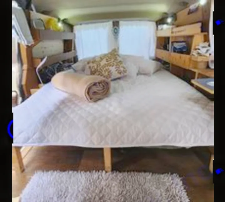 Spacious, cozy bed in an RV rental's interior, featuring built-in storage and curtains. Ideal camper accommodation.. Chevrolet Open Road 2000