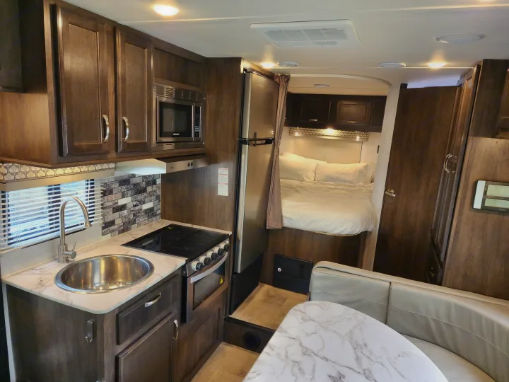 RV rental interior: A compact kitchen with sink, stove, microwave, plus a cozy bedroom and dining area. Perfect for travel.. Gulf Stream Conquest 2021