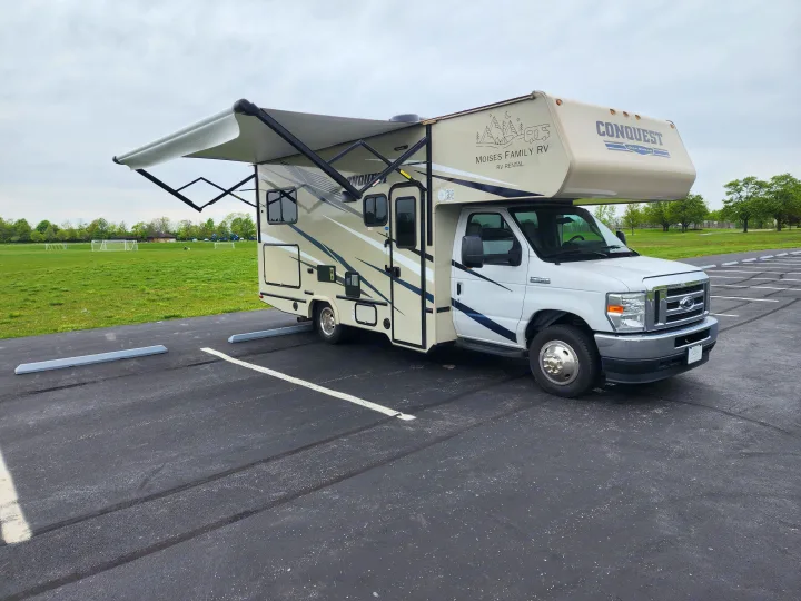 Moises Family RV rental, a Conquest RV, parked with awning extended beside a large grassy field.. Gulf Stream Conquest 2021