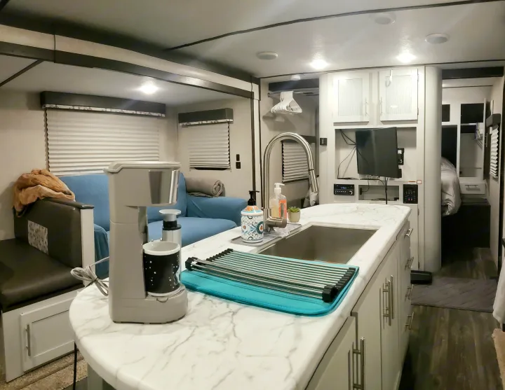 This modern RV rental features a well-equipped kitchen, comfortable living area with a couch, and a glimpse into the private bedroom.. Keystone RV Bullet Ultra Lite 2020