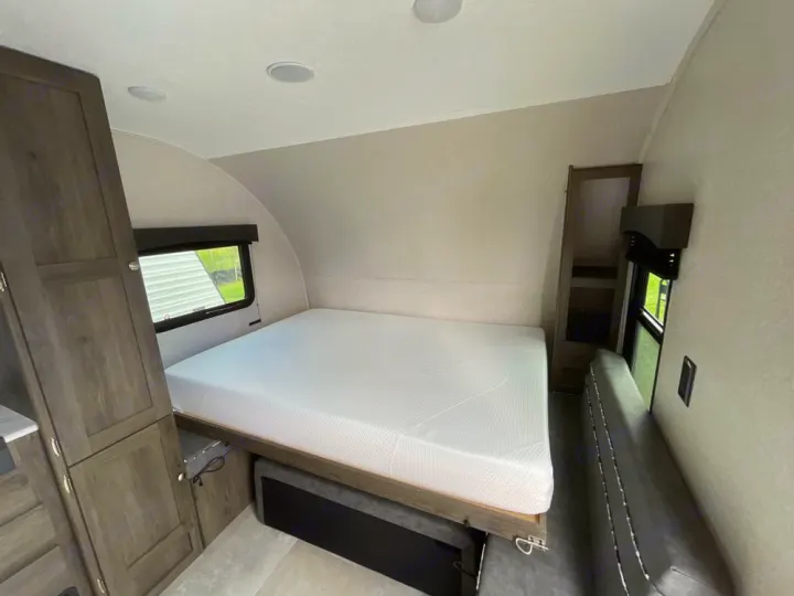 Step inside this clean RV rental, showcasing a comfy bed, gray couch, and storage – your perfect camper escape!. Independence Trail 188DBK 2022