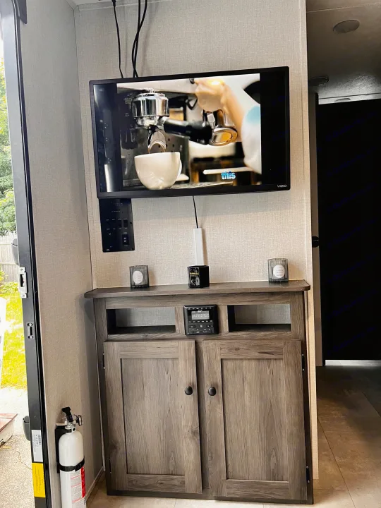RV rental living space: TV, control panel, and storage cabinet provide comfort for travel in this cozy interior.. Independence Trail 188DBK 2022
