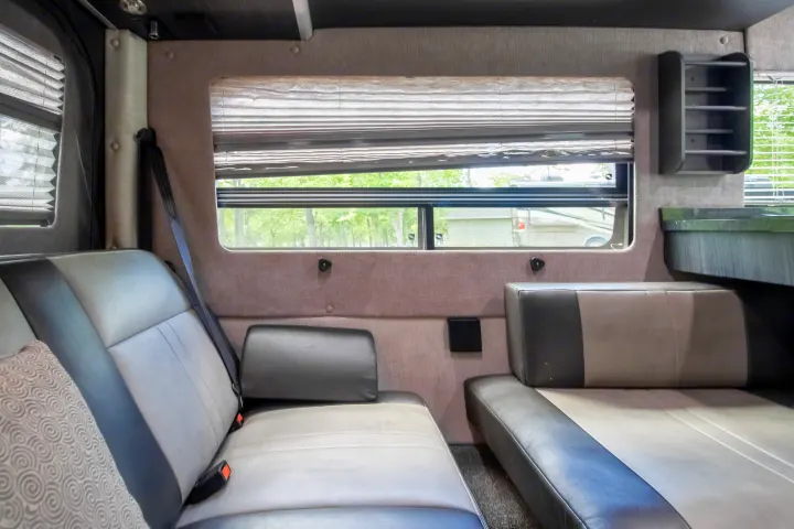 Inside an rv rental: inviting grey and black seating, a window with privacy blinds, and convenient storage solutions.. Roadtrek Roadtrek Class B 2017