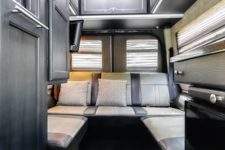 Experience comfort in this RV rental's modern interior, featuring L-shaped seating, windows with blinds, a TV, and sleek cabinetry.. Roadtrek Roadtrek Class B 2017