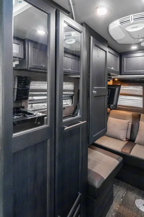 Explore this modern RV rental interior with dark wood cabinets, a comfy dinette, kitchenette, and efficient Dometic AC.. Roadtrek Roadtrek Class B 2017