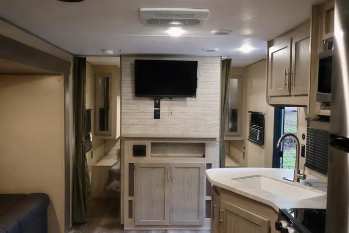 Inside a modern **rv rental**: bright living area with TV, full kitchen, and glimpse of cozy sleeping quarters.. Coachmen Other 2023