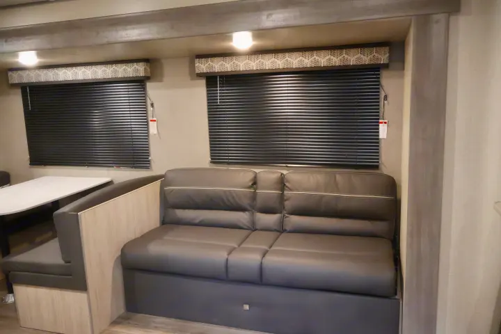 RV rental interior: Compact living space with dinette and dark gray sofa seating by windows.. Coachmen Other 2023