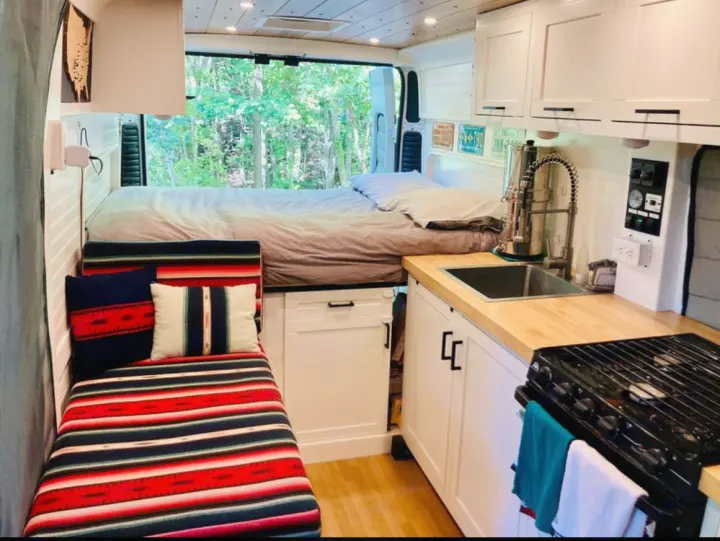 Modern RV rental interior: cozy bed, full kitchen, and colorful bench seating, ideal for travel.. Dodge Other 2017