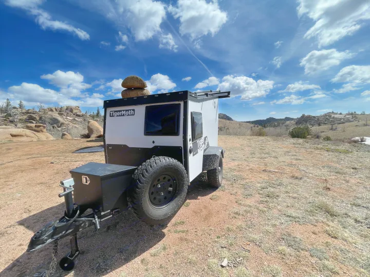 Ready for adventure: This white TigerMoth off-road RV rental camper is parked in a rugged, scenic landscape.. TAXA Outdoors Tigermoth Camper 2021