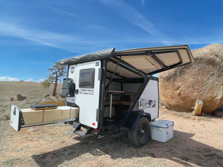 Compact Taxa TigerMoth trailer, ideal for RV rental, set up for remote camping amidst rocks and open land.. TAXA Outdoors Tigermoth Camper 2021