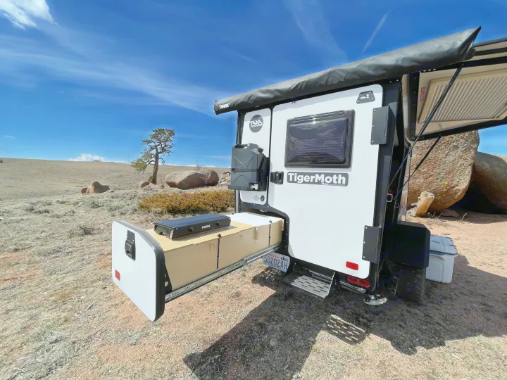 TigerMoth RV rental camping trailer with pull-out kitchen, set up for outdoor adventure.. TAXA Outdoors Tigermoth Camper 2021