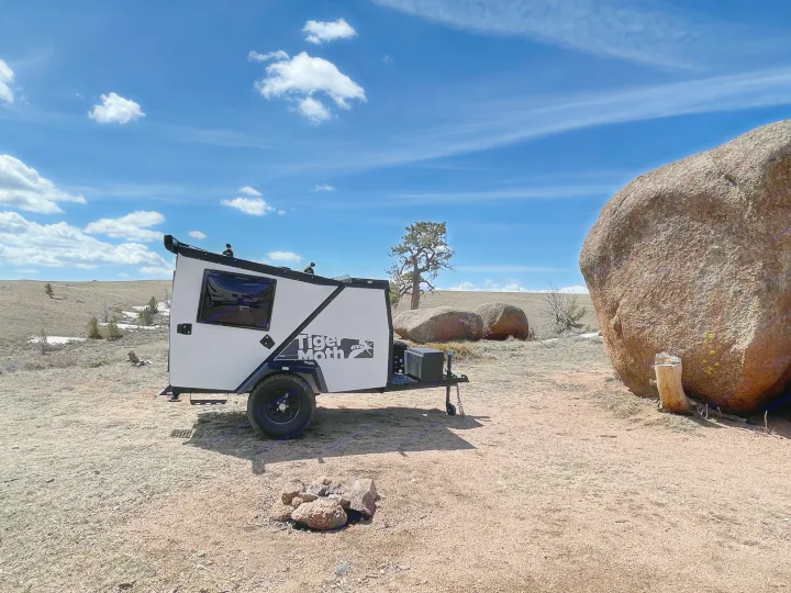 White Tiger Moth rv rental camper trailer parked in a rocky outdoor landscape under a blue sky.. TAXA Outdoors Tigermoth Camper 2021