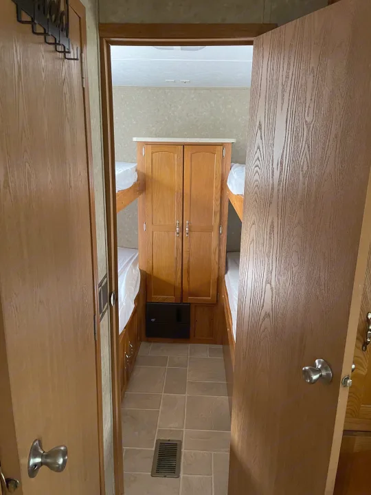 RV rental interior: A cozy bunkhouse area with bunk beds on both sides, a central cabinet, and tiled floor.. Puma 30DBSS 2009