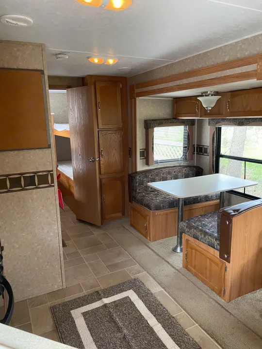 Inside an RV rental, showing the cozy dinette with patterned cushions, bunk beds, and wood-paneled interior. A comfortable travel space.. Puma 30DBSS 2009