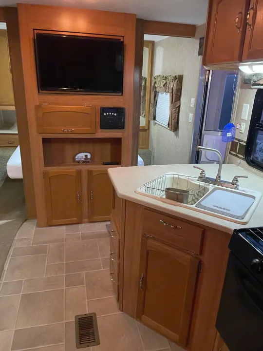 Spacious RV rental interior featuring a full kitchen with sink, cabinetry, and a cozy entertainment center with TV. Perfect for your next trip.. Puma 30DBSS 2009
