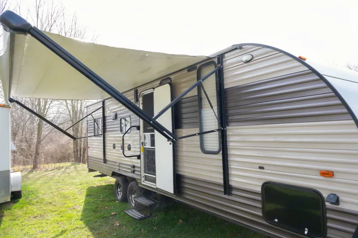 Modern RV rental parked on green grass with awning out, ready for your camping trip.. Forest River Cherokee Grey Wolf 2018