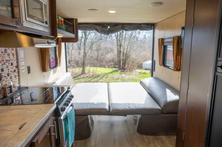 Modern rv rental interior showcasing a kitchen, convertible living/sleep area, and scenic outdoor view from a large window.. Forest River Cherokee Grey Wolf 2018