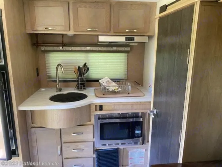 Inside an RV rental: a modern, compact kitchen featuring a sink, microwave, and light wood cabinets.. Forest River R-Pod 2020
