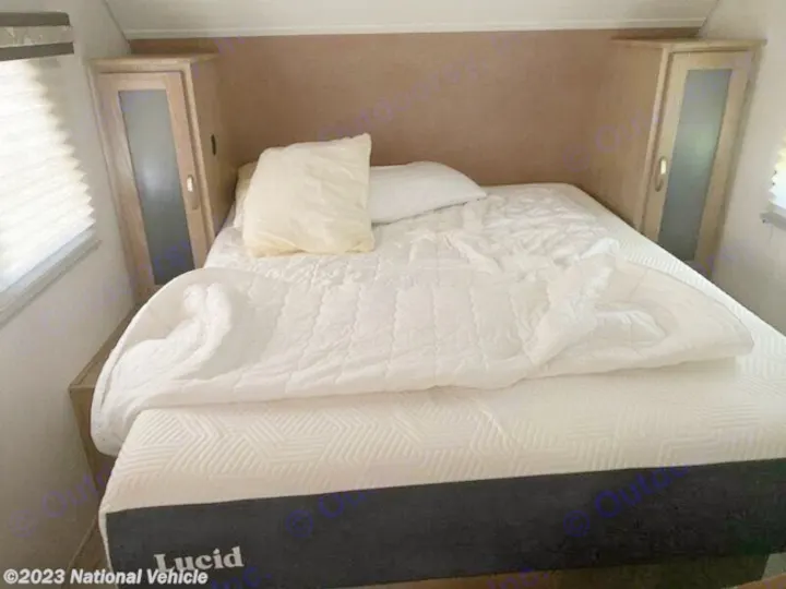RV rental bedroom: Cozy bed with white comforter, pillows, and Lucid mattress, flanked by built-in cabinets.. Forest River R-Pod 2020