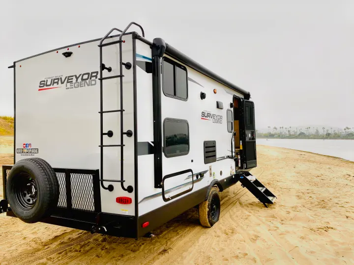 Explore with an RV rental! This modern travel trailer is perfectly situated on a serene sandy beach, ready for your next adventure.. Forest River Surveyor Legend 2023