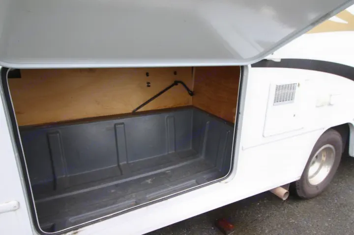 Open RV rental exterior storage compartment with a durable molded liner. Provides ample space for your travel gear.. Winnebago Access 2011