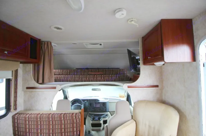 Spacious RV rental interior featuring an over-cab bunk, driver's area, comfortable seating, and storage cabinets.. Winnebago Access 2011