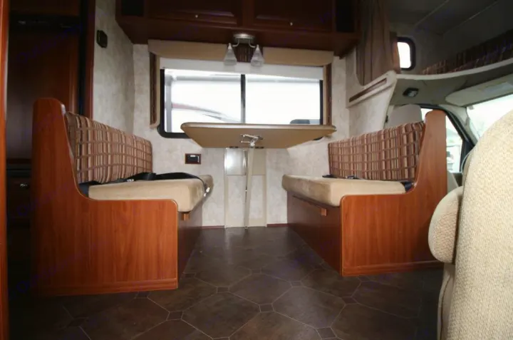 RV rental interior: A bright dinette area features two facing benches with patterned backrests and a central table, equipped with seatbelts.. Winnebago Access 2011