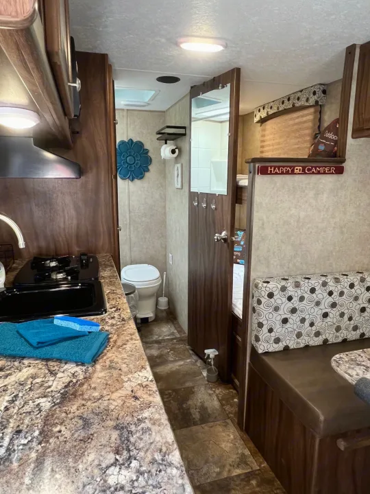 Functional RV rental interior showing a kitchen, compact bathroom, and cozy dinette with adjacent bunk beds for travel.. Coachmen Clipper 2016