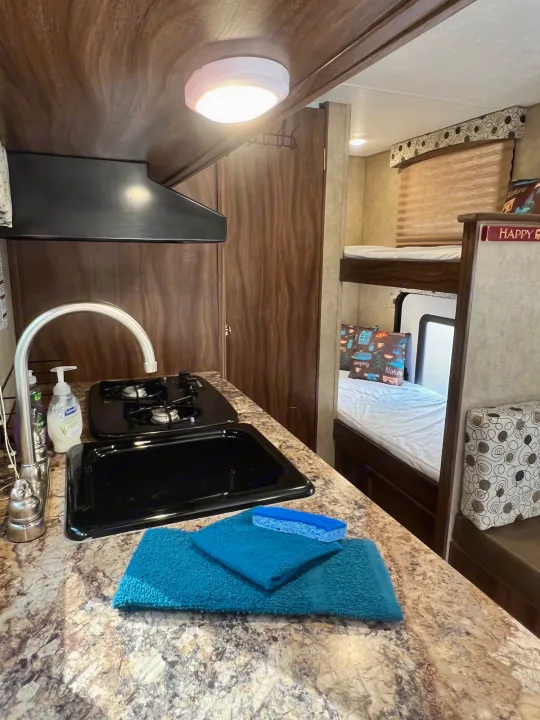 This RV rental features a functional kitchen with sink/stove, cozy bunk beds, and a dining nook.. Coachmen Clipper 2016
