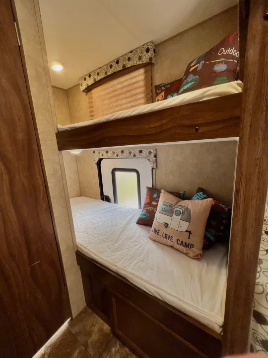 This RV rental features comfy bunk beds, decorated with camping pillows, and a bright window.. Coachmen Clipper 2016