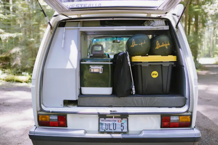 RV rental ready for adventure: VW Westfalia with cooler, storage, and sleeping bags visible through open rear hatch.. Volkswagen Westfalia 1990