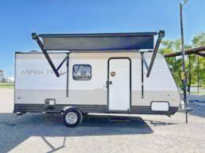 This compact white and grey travel trailer with an extended awning is ideal for your next RV rental adventure.. Aspen Trail 17BH 2021