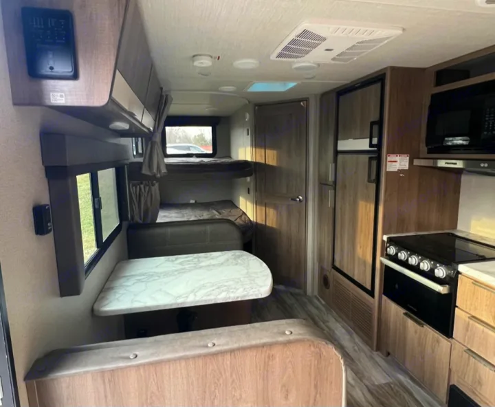 RV rental interior: dining booth, bunk beds, full kitchen with oven, microwave, and fridge. Wood finishes, modern design.. Grand Design Imagine XLS 2021