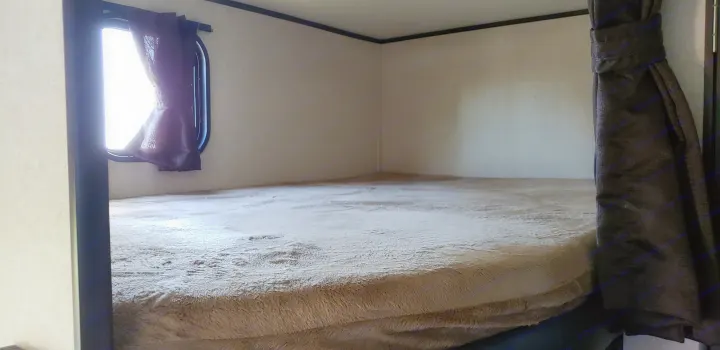Inside an RV rental: a cozy bunk bed with a bright window and soft, plush blanket.. Jayco Jay Flight SLX 2018