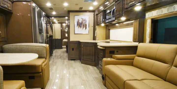 Spacious, modern RV rental interior featuring a full kitchen, dining booth, and living area with recliners, tiled floor.. Entegra Coach Reatta 2021