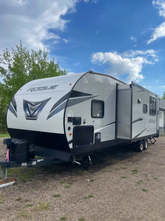 A spacious Forest River Rogue travel trailer RV with a slide-out, parked on gravel, perfect for your next rv rental adventure.. Forest River Vengeance 2022
