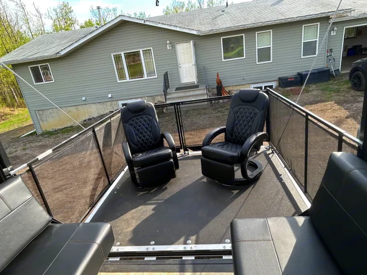 Inside an RV rental's rear patio deck, featuring two swivel chairs & integrated benches. Overlooks a residential home.. Forest River Vengeance 2022
