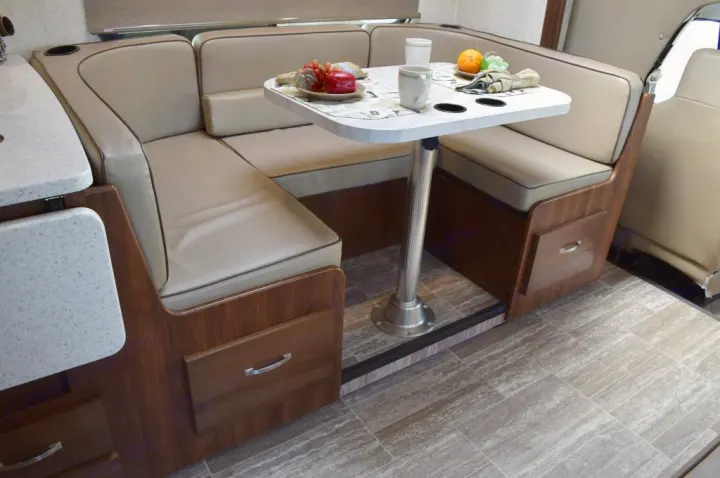 This RV rental features a U-shaped dinette with beige cushioned seating, a white table with cups and fruit, and wood storage.. Forester Forester Motorhome 2020