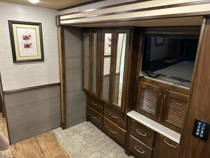 Spacious RV rental bedroom: modern wood cabinetry, mirrored wardrobe, TV, and smart controls offer ample storage and comfort.. Allegro Allegro Open Road 2019