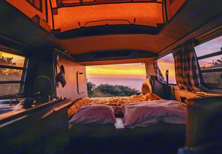 Cozy RV rental interior with bed facing a stunning ocean sunset. Ideal for your next van life adventure!. Volkswagen T2 Westfalia 1971