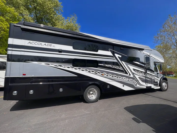 Luxury Accolade XL RV rental, a sleek black, grey, and white motorhome with bold graphics, parked under a clear sky.. Entegra Coach Accolade XL 37L  Super-C 2023