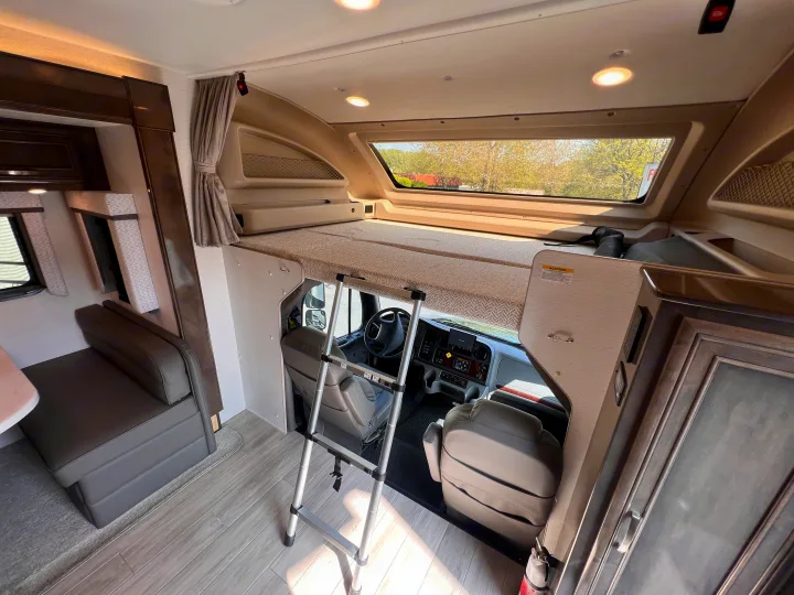 Bright rv rental interior, showcasing the cab-over bunk with ladder, driver's area, and a comfortable dinette.. Entegra Coach Accolade XL 37L  Super-C 2023