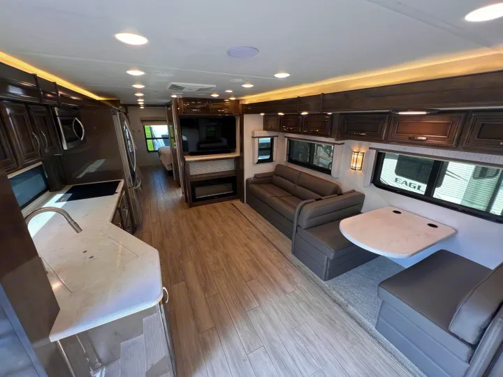 Spacious rv rental interior featuring a modern kitchen, comfortable living area with sofa, and dining booth. Ideal for travel.. Entegra Coach Accolade XL 37L  Super-C 2023